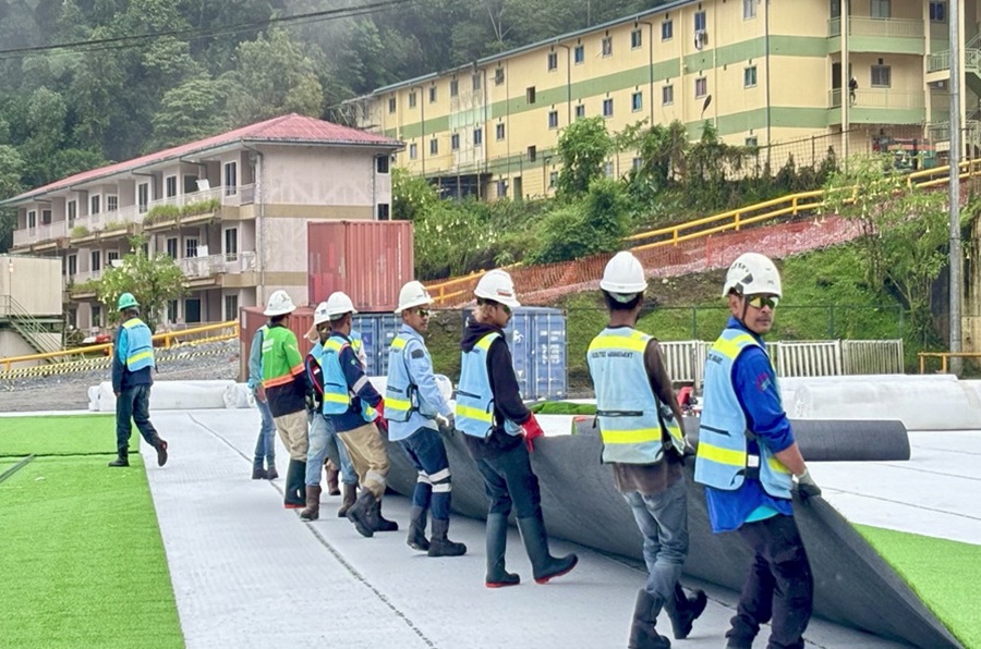 Facilities &Town Management workers are spreading rolls of grass over layers of torcelain.
